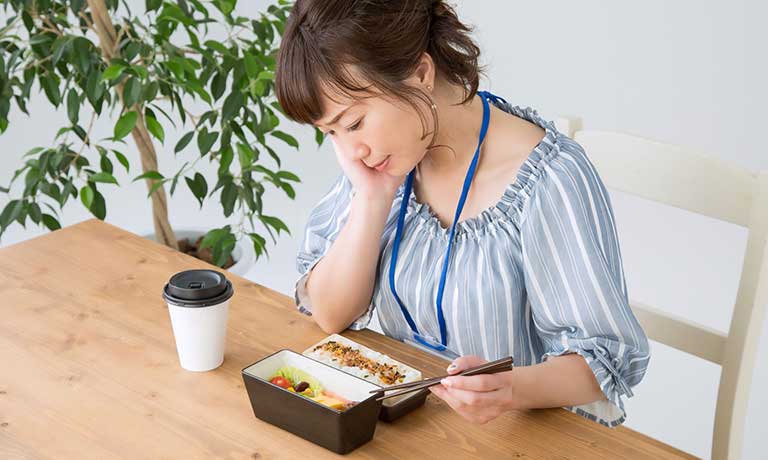 頬杖をつく食事中の女性